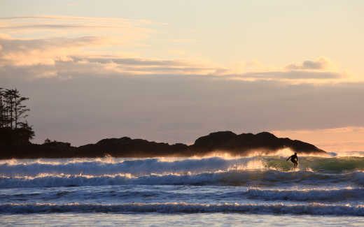 Les vagues et un surfeur au coucher du soleil, Tofino, Colombie-Britannique, Canada.
