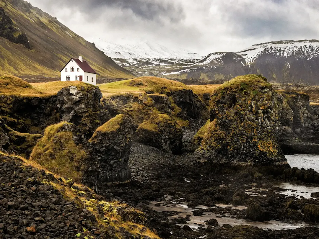 Einsames weißes Haus auf Klippen mit Lavaformationen. Arnarstapi, Snæfellsnes, Island.