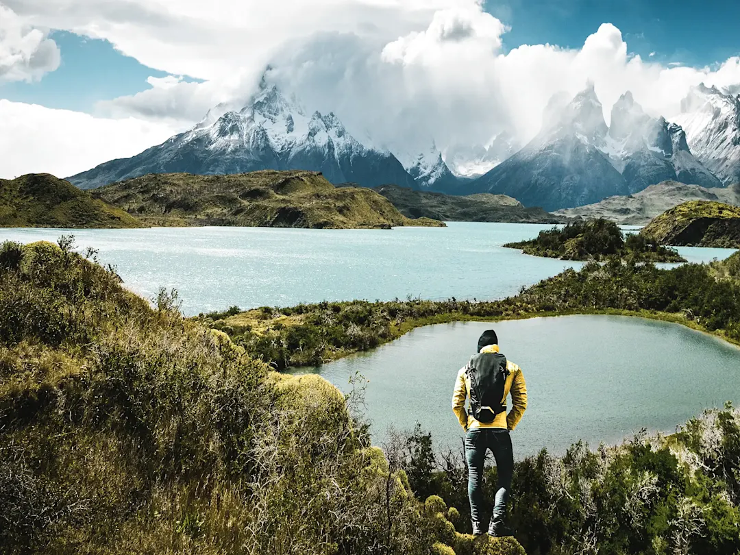 Wanderer mit Blick auf türkisfarbene Seen und schroffe Berge. Torres del Paine, Chile.
