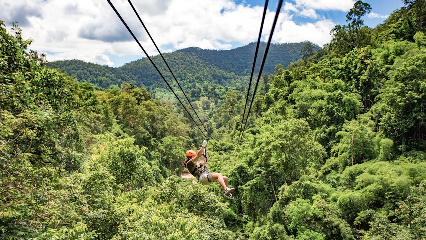 Mauritius, Ziplining Person mit Helm und Gurt rutscht an einer Seilrutsche über einen tropischen Dschungel. Mauritius.