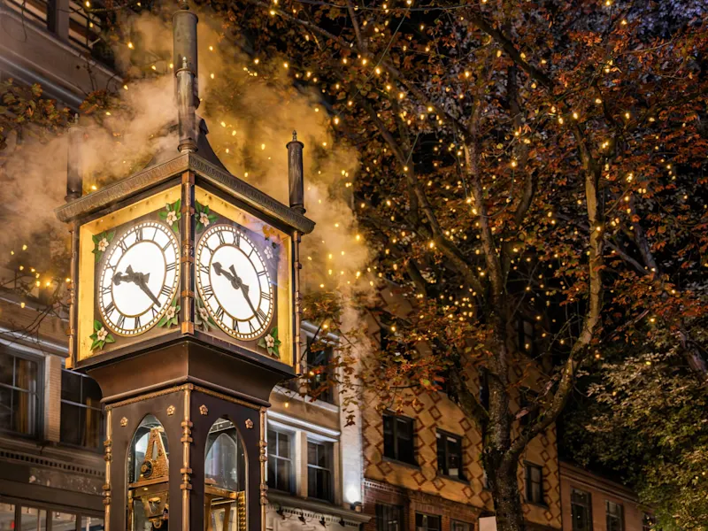 Vancouver, British Columbia, Kanada Die dampfende Gastown-Dampfuhr bei Nacht, umgeben von Lichtern und herbstlichen Bäumen. Vancouver, British Columbia, Kanada.