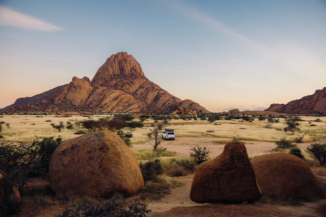 Luftaufnahme eines Wohnmobils in der spektakulären Wüstenlandschaft der Spitzkoppe in Namibia bei Sonnenaufgang