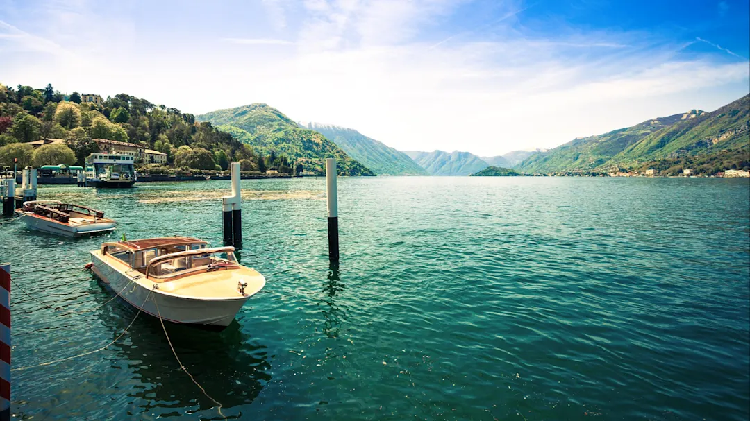 Bootsstege am Lago di Como mit Aussicht auf die umliegenden Berge, Oberitalienische Seen, Italien.
