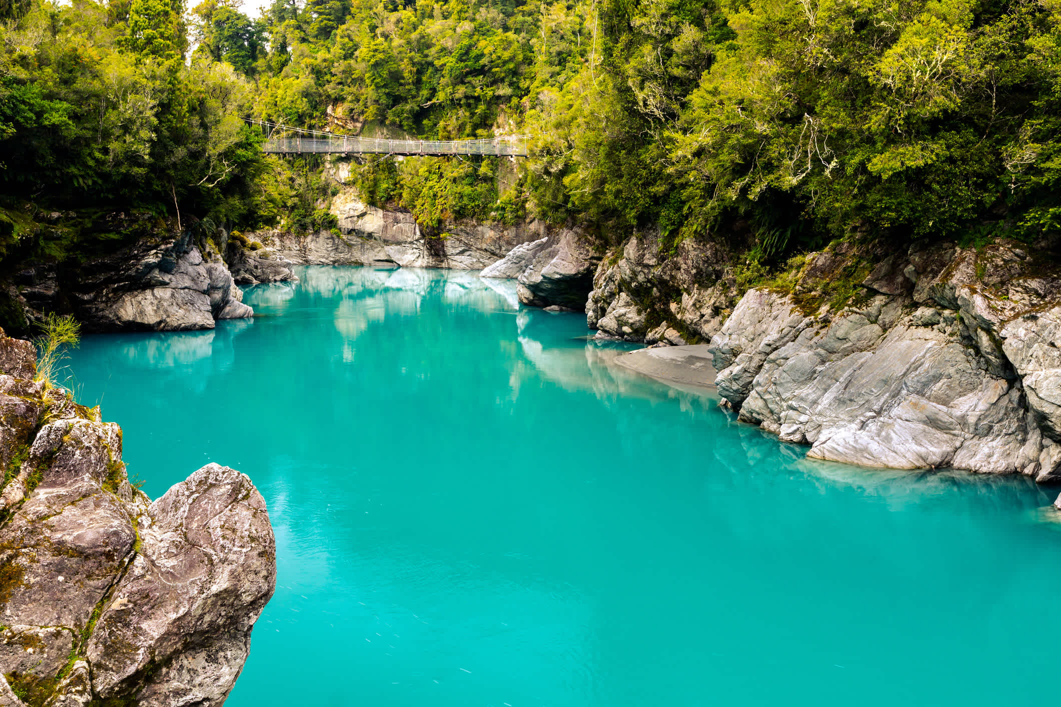 Les eaux turquoises de la rivière Hokitika avec un pont tournant en arrière-plan, près de Hokitika, Aotearoa, en Nouvelle-Zélande.
