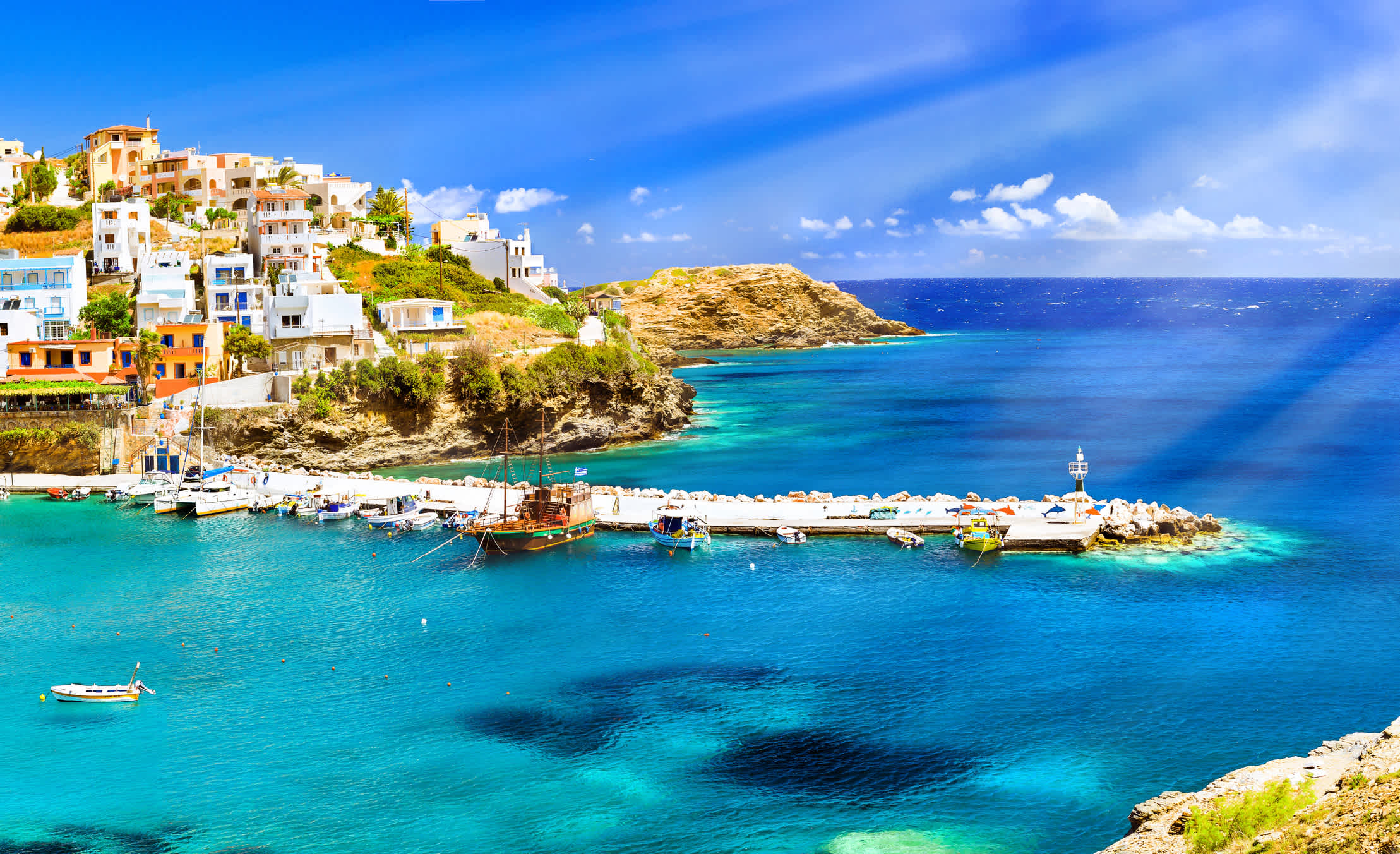Eine idyllische Bucht auf Kreta mit kristallklarem Wasser und bunten Häuser entlang der Küste