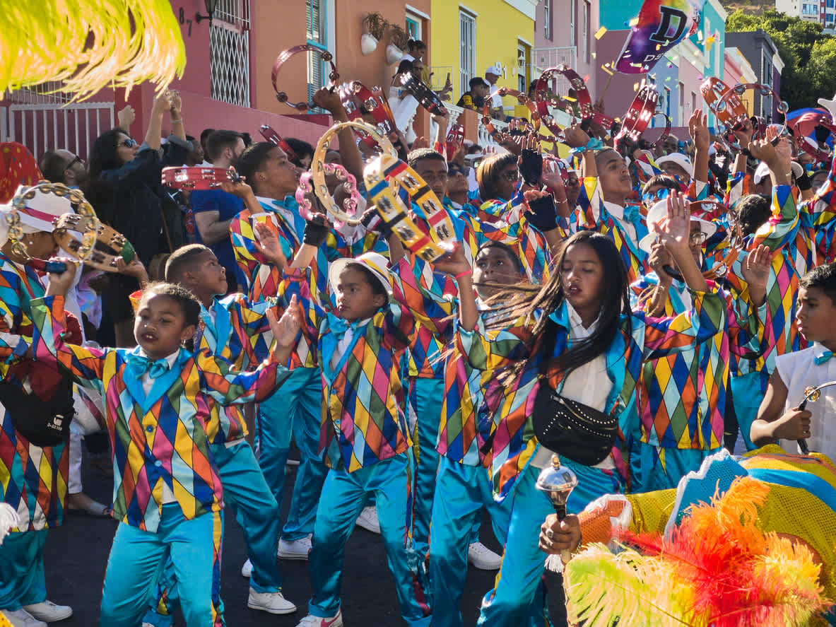 Groupe d'enfants en train de danser et de défiler pendant le carnaval du Cap en Afrique du Sud surnommé Kaapse Klopse.