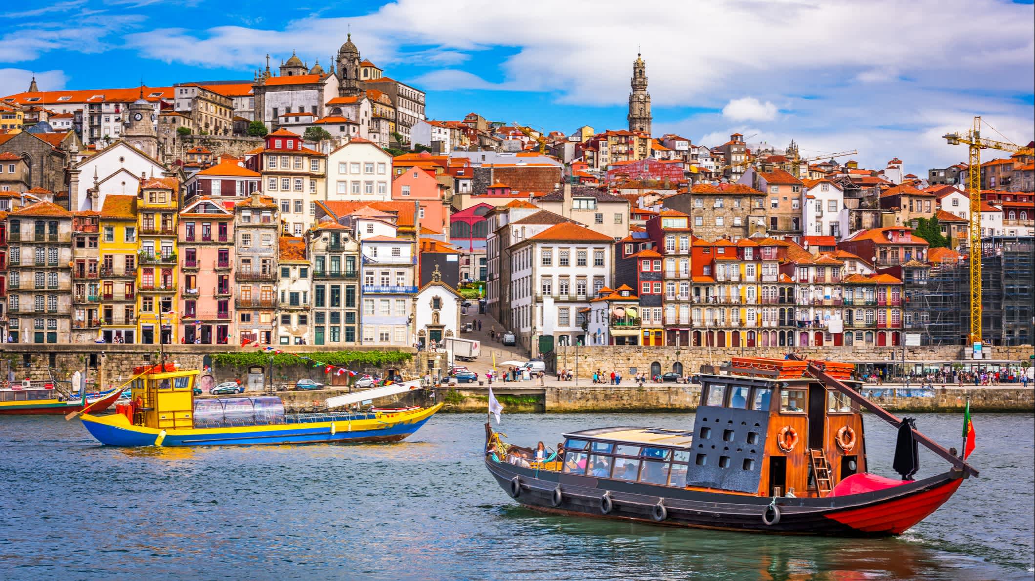 Bateaux colorés sur le fleuve Douro avec la vieille ville en arrière-plan, à Porto, au Portugal.

