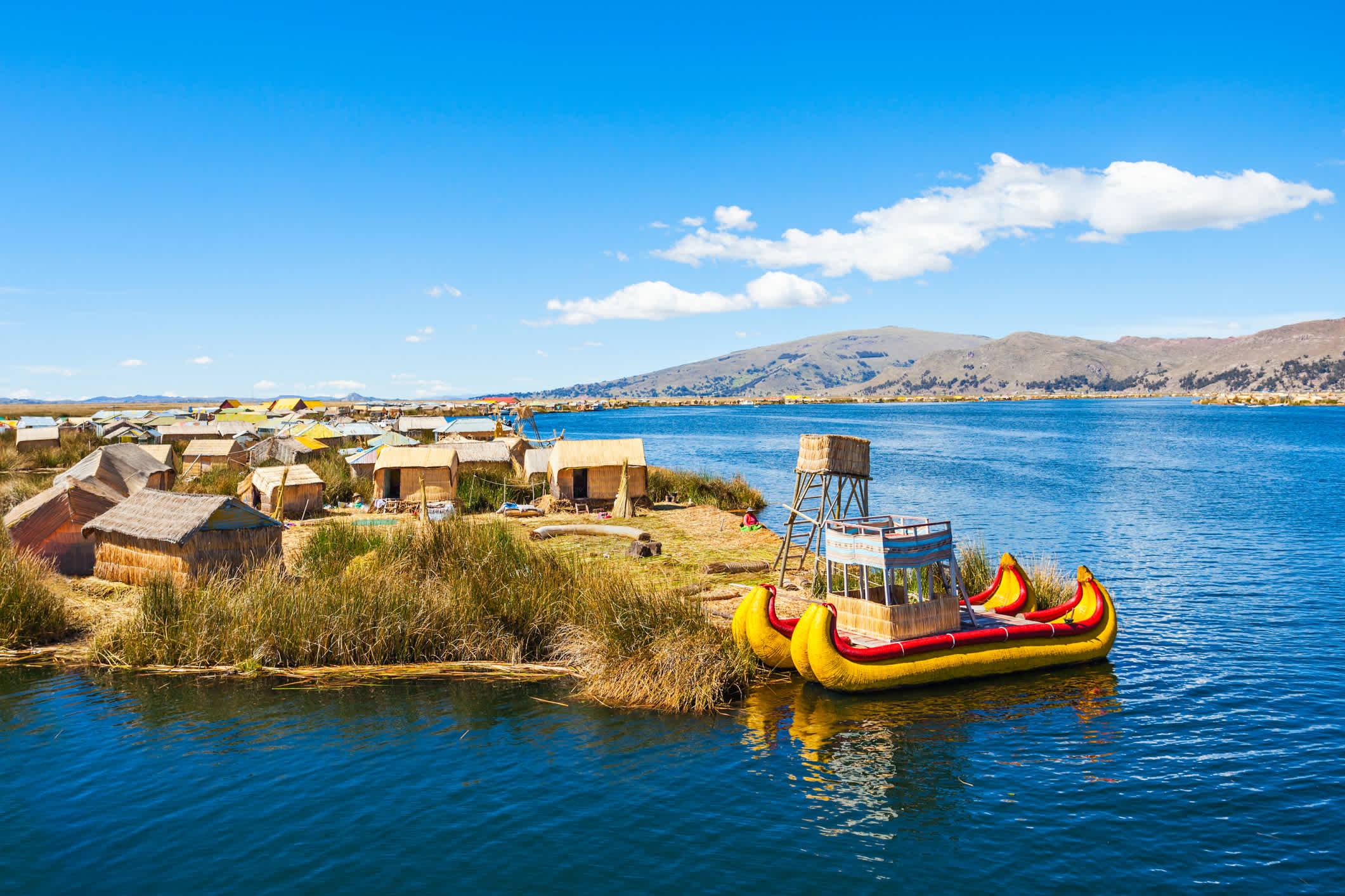 Kleine Insel und traditionelles Boot auf dem ikonischen Titicacasee in Peru
