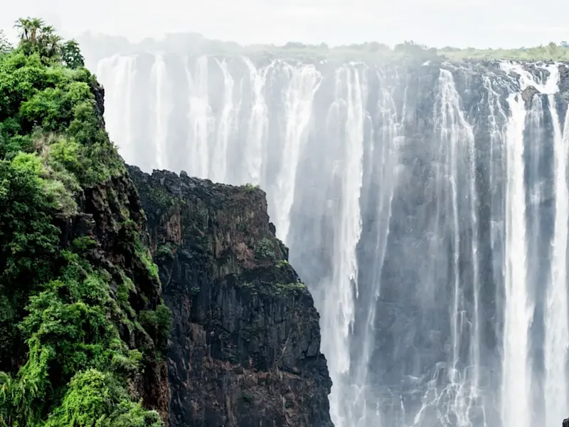 Botswana, Victoriafälle Spektakulärer Wasserfall zwischen grünen Felsen mit Nebel. Victoriafälle, Botswana.