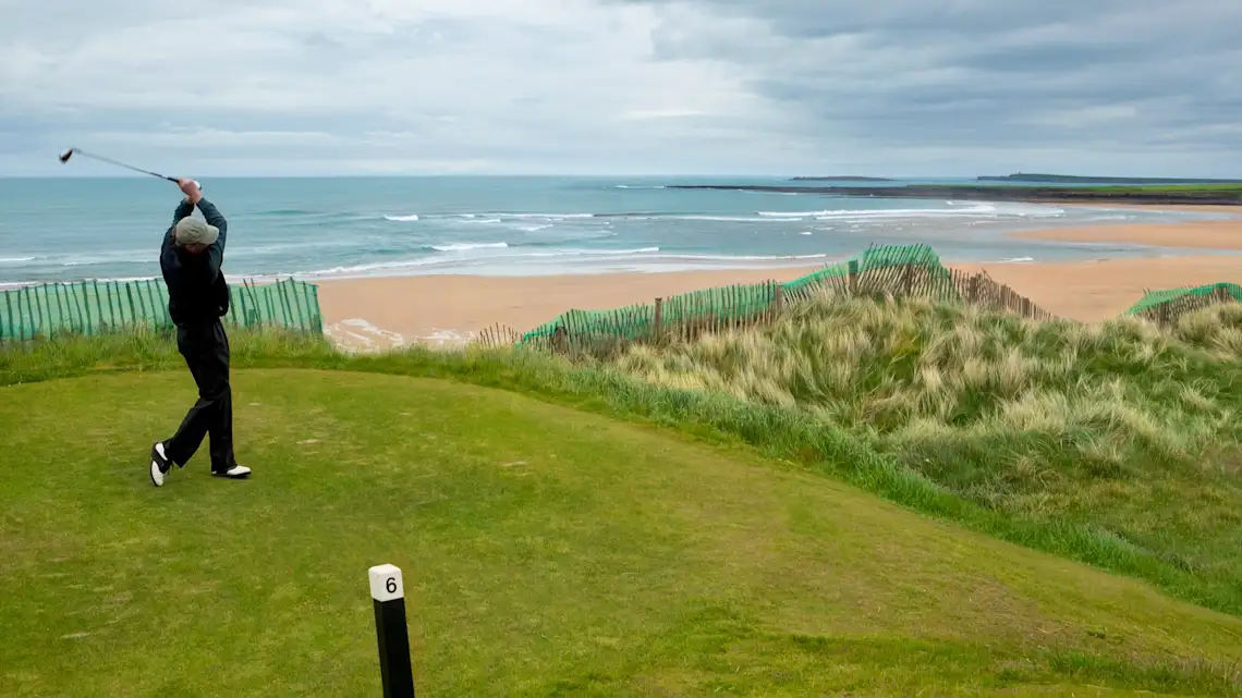 Irland, Golfen, Golfer Golfer auf einem Linksplatz beim Abschlag mit Meer im Hintergrund
