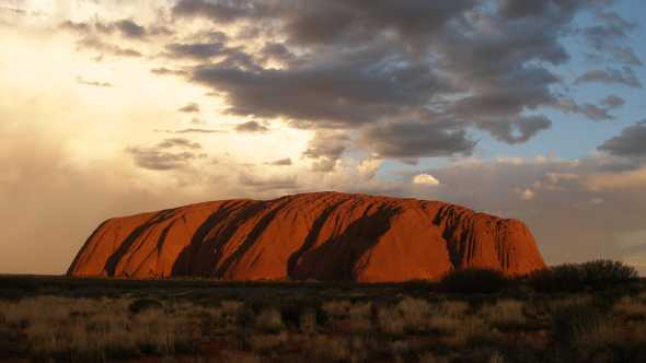 Visit Ayers Rock, pictured here under clouds, on an Outback tour