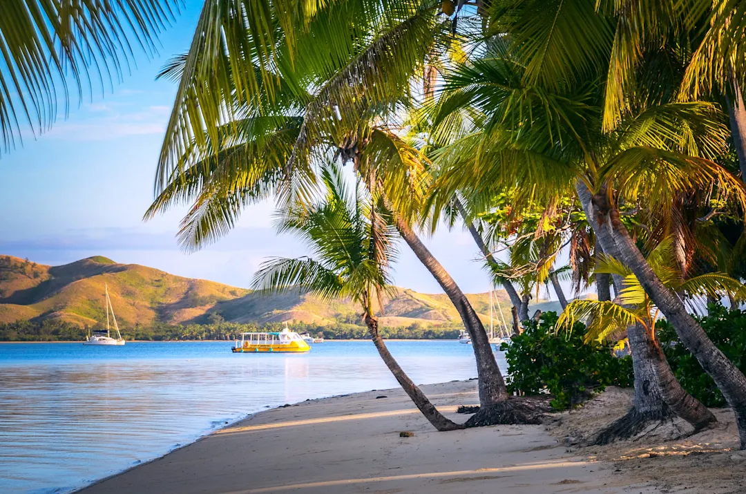 Strand mit Palmen und Boot im Hintergrund, Fidschi.
