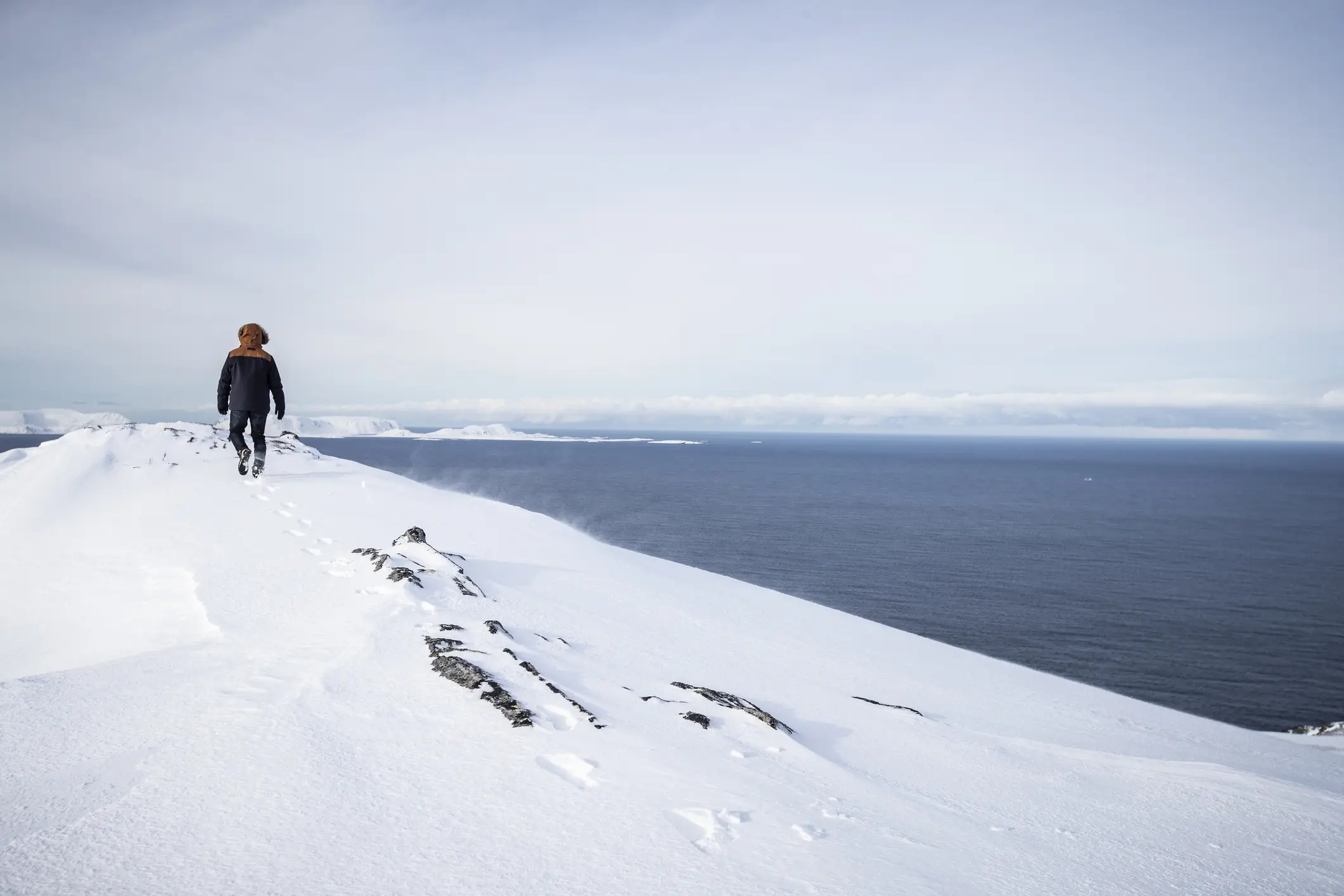 Mann wander im Schnee mit Blick aufs Meer