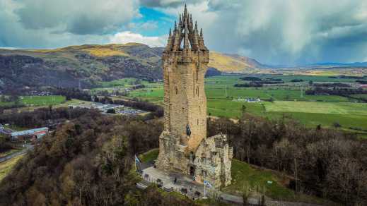 Luftaufnahme des Turms National Wallace Monument mit grüner Hügel- und Wiesenlandschaft im Hintergrund