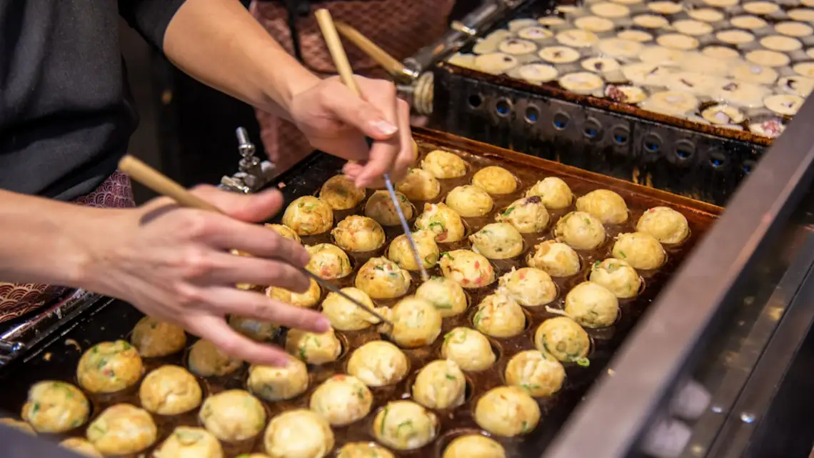 Japan, Takoyaki Takoyaki werden an einem Straßenstand zubereitet