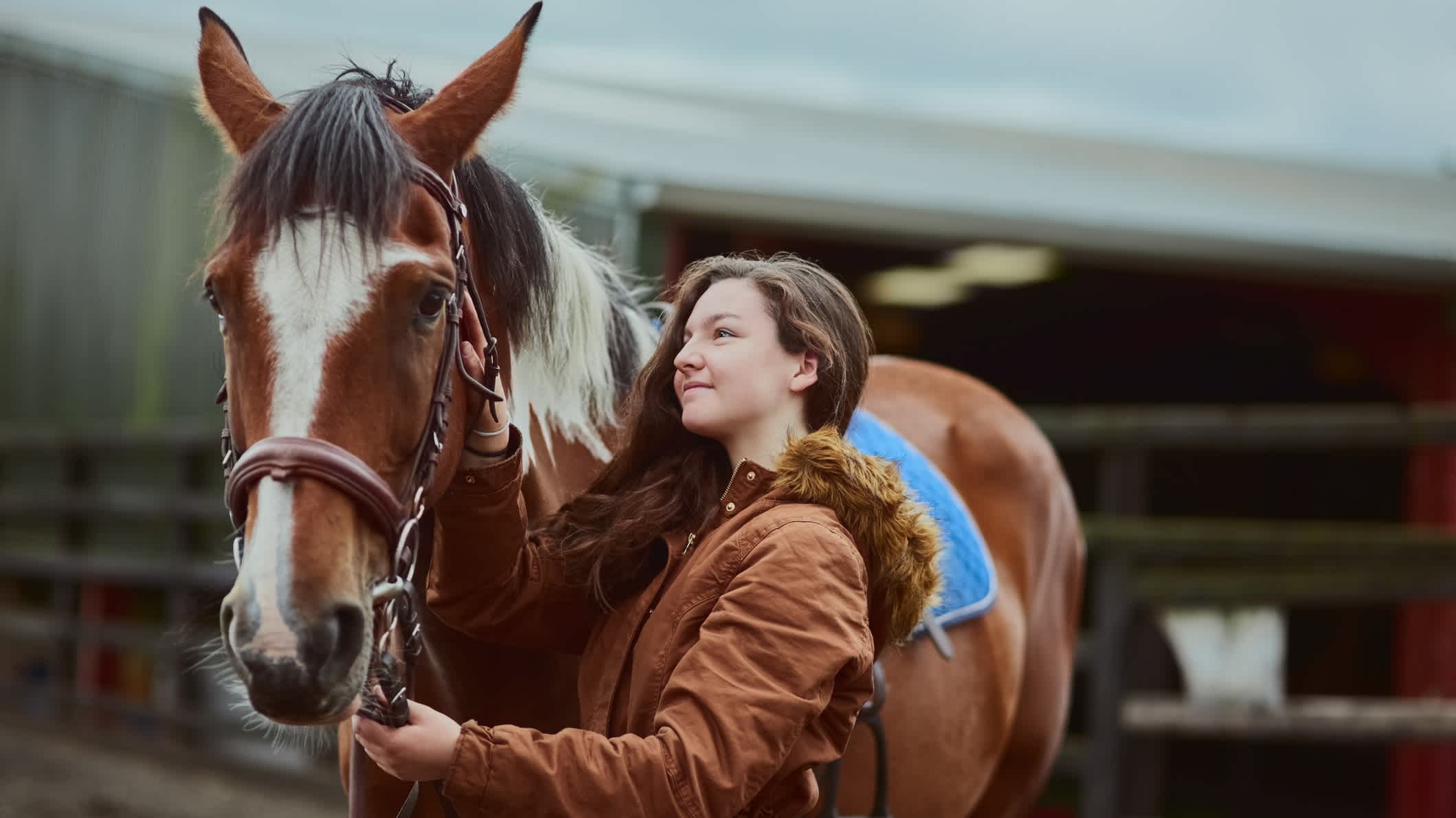 Aufnahme eines Teenagers, das neben ihrem Pony auf einer Farm steht

