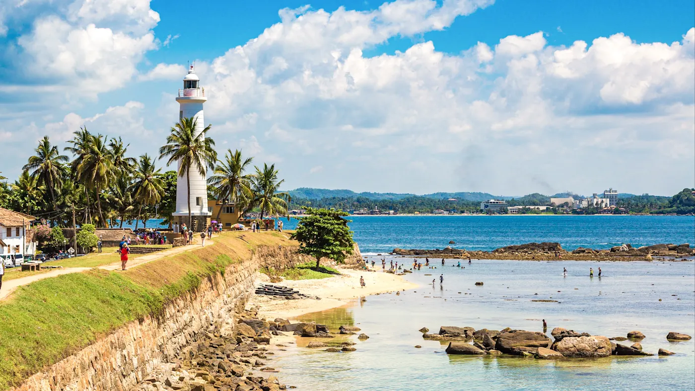 Galle, Südprovinz, Sri Lanka Weißer Leuchtturm am Meer mit Palmen und Besuchern. Galle, Südprovinz, Sri Lanka.