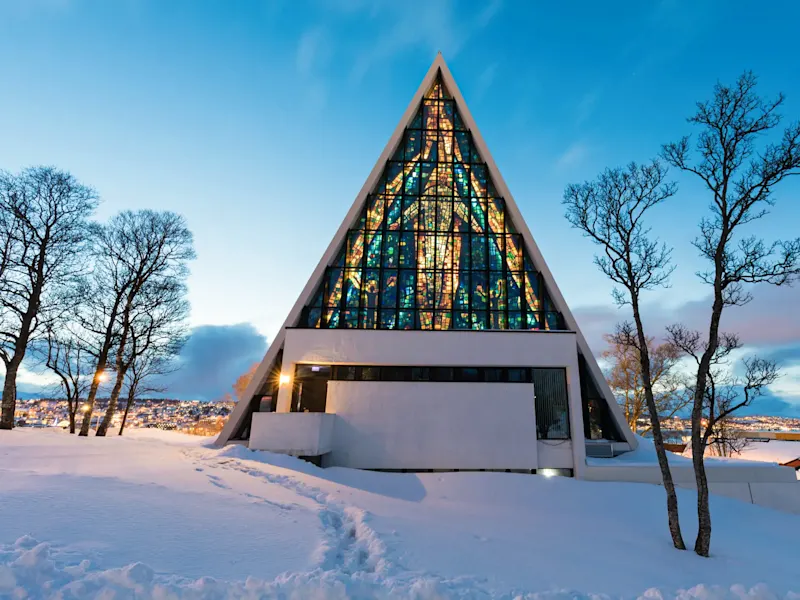 Die Eismeerkathedrale mit buntem Glasfenster in winterlicher Landschaft. Tromsø, Troms, Norwegen.