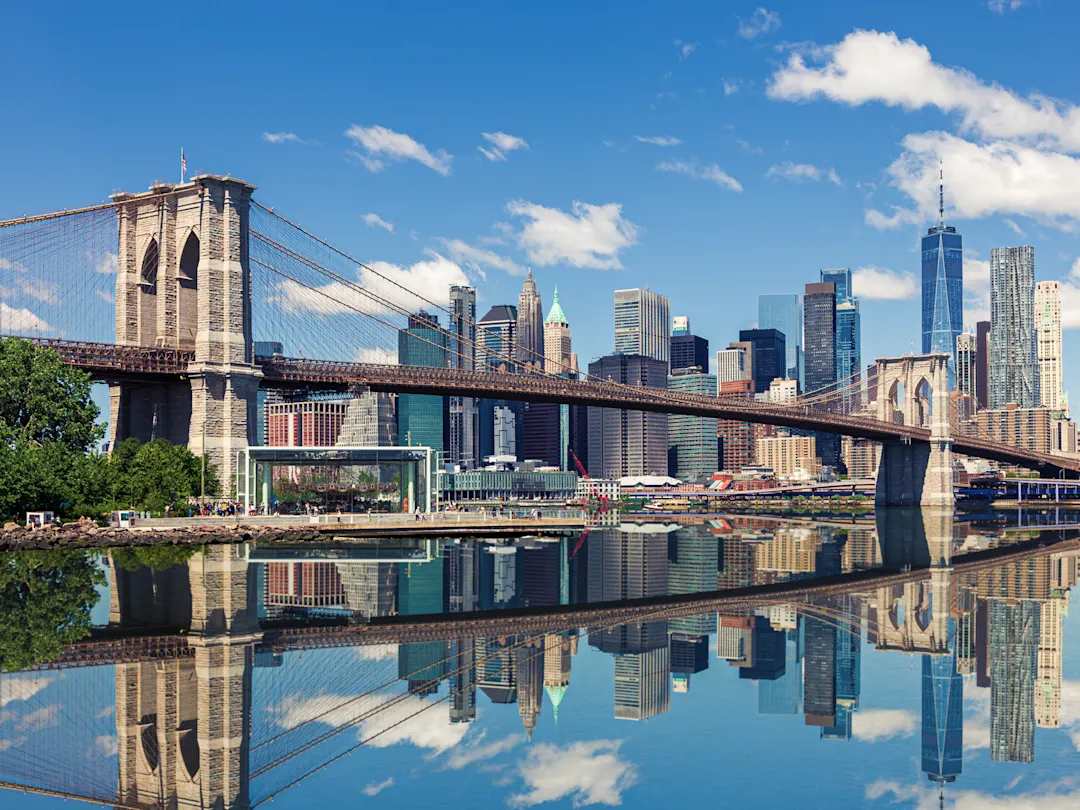 Brooklyn Bridge mit Skyline von Manhattan im Hintergrund und Spiegelung im Wasser, New York City, USA.
