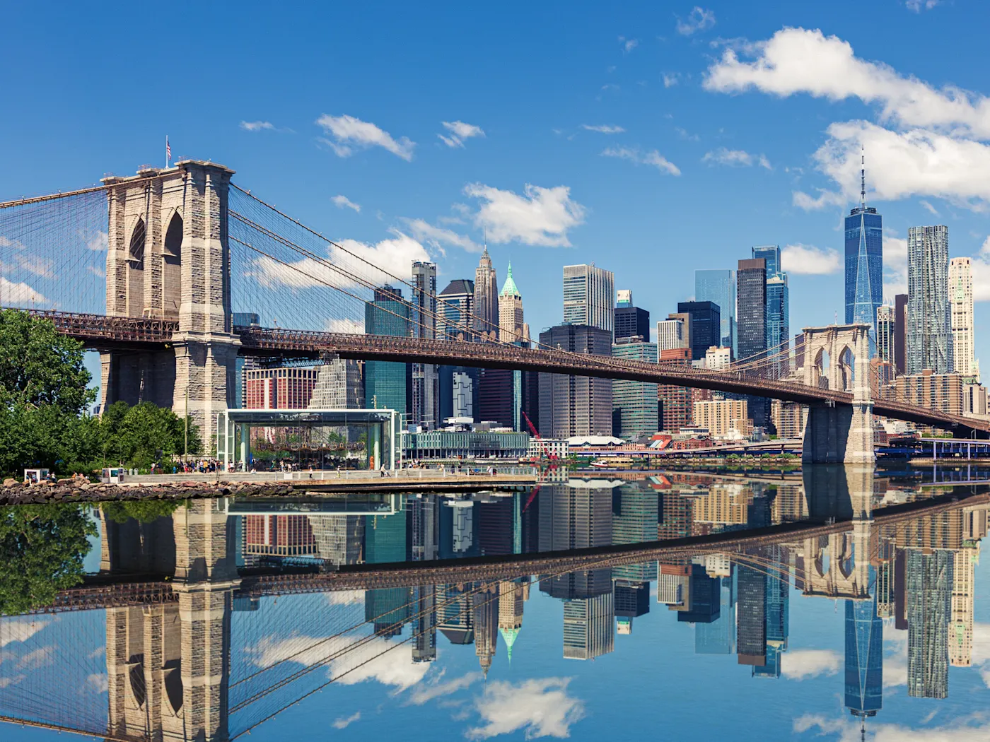 Brooklyn Bridge mit Skyline von Manhattan im Hintergrund und Spiegelung im Wasser, New York City, USA.