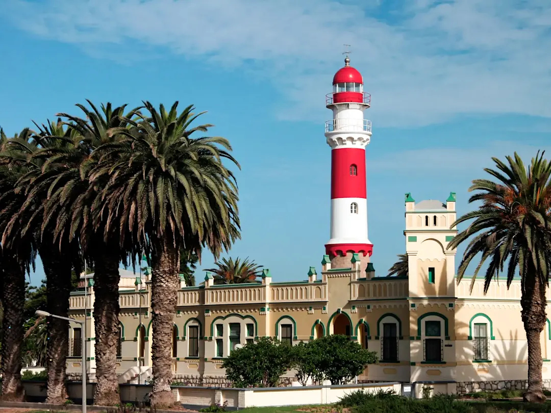 Historischer rot-weißer Leuchtturm mit Palmen. Swakopmund, Erongo, Namibia.