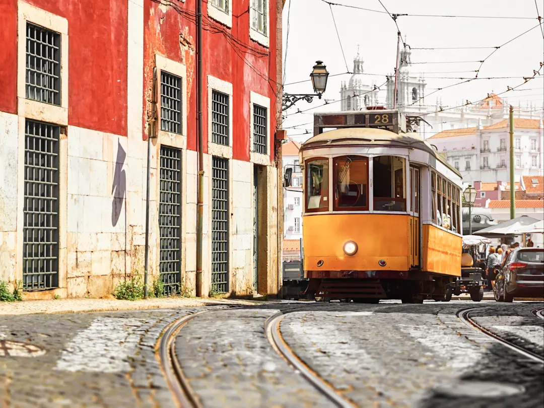 Gelbe Straßenbahn fährt durch eine historische Straße in Lissabon. Lissabon, Portugal.

