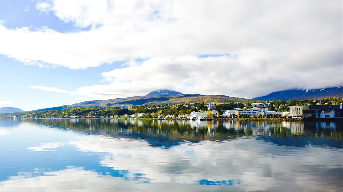 Akureyri, Nordisland, Island Spiegelung einer Stadt mit Bergen im Hintergrund in einem See. Akureyri, Nordisland, Island.