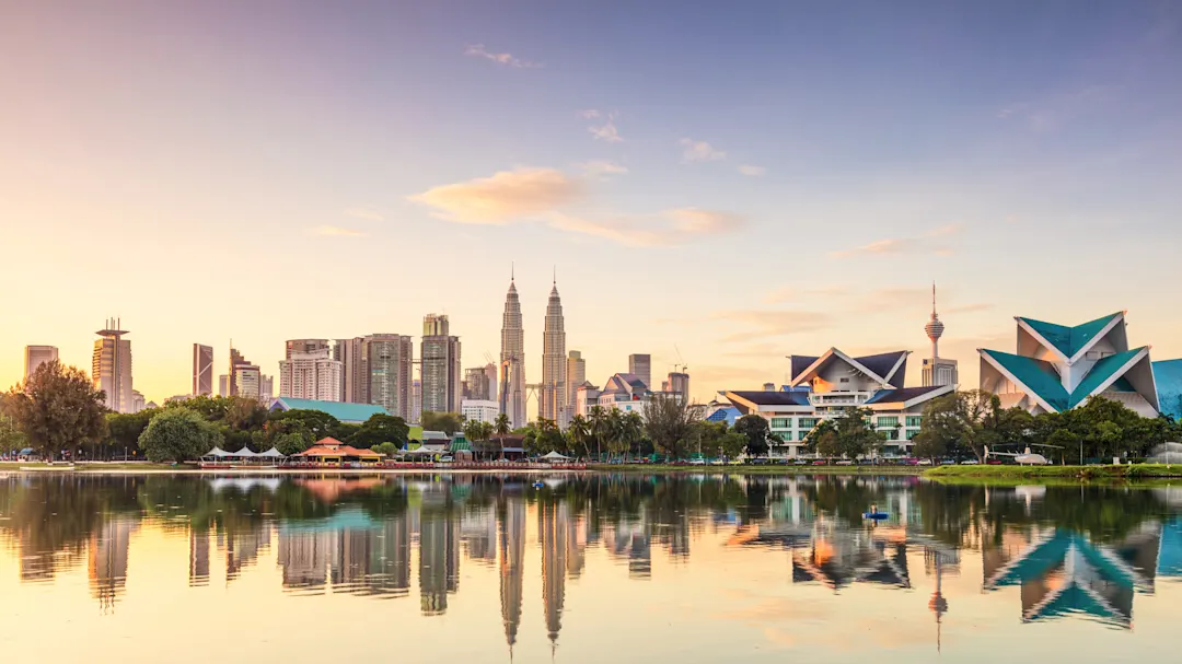 Skyline von Kuala Lumpur mit den Petronas Towers und Spiegelung im Wasser bei Sonnenuntergang. Kuala Lumpur, Malaysia.
