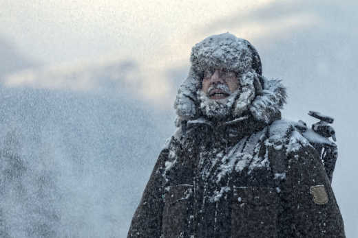 Mann mit pelzigem Schneesturm mit bewölktem Himmel und Schneeflocken