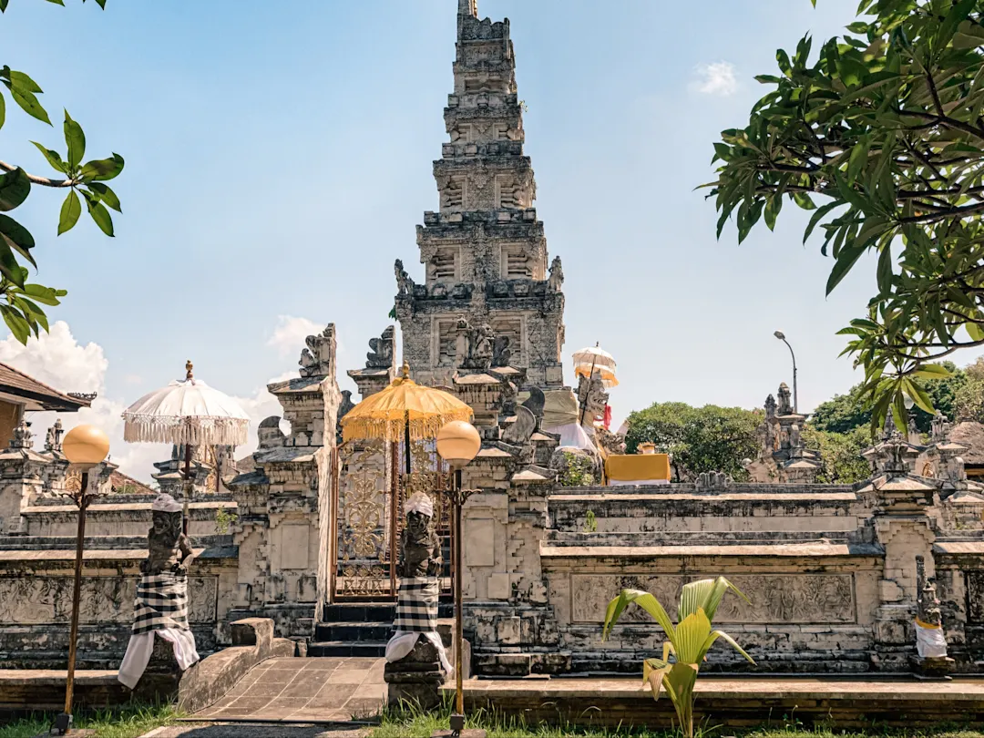 Balinesischer Tempel mit verzierten Toren und Opfergaben unter blauem Himmel. Denpasar, Bali, Indonesien.
