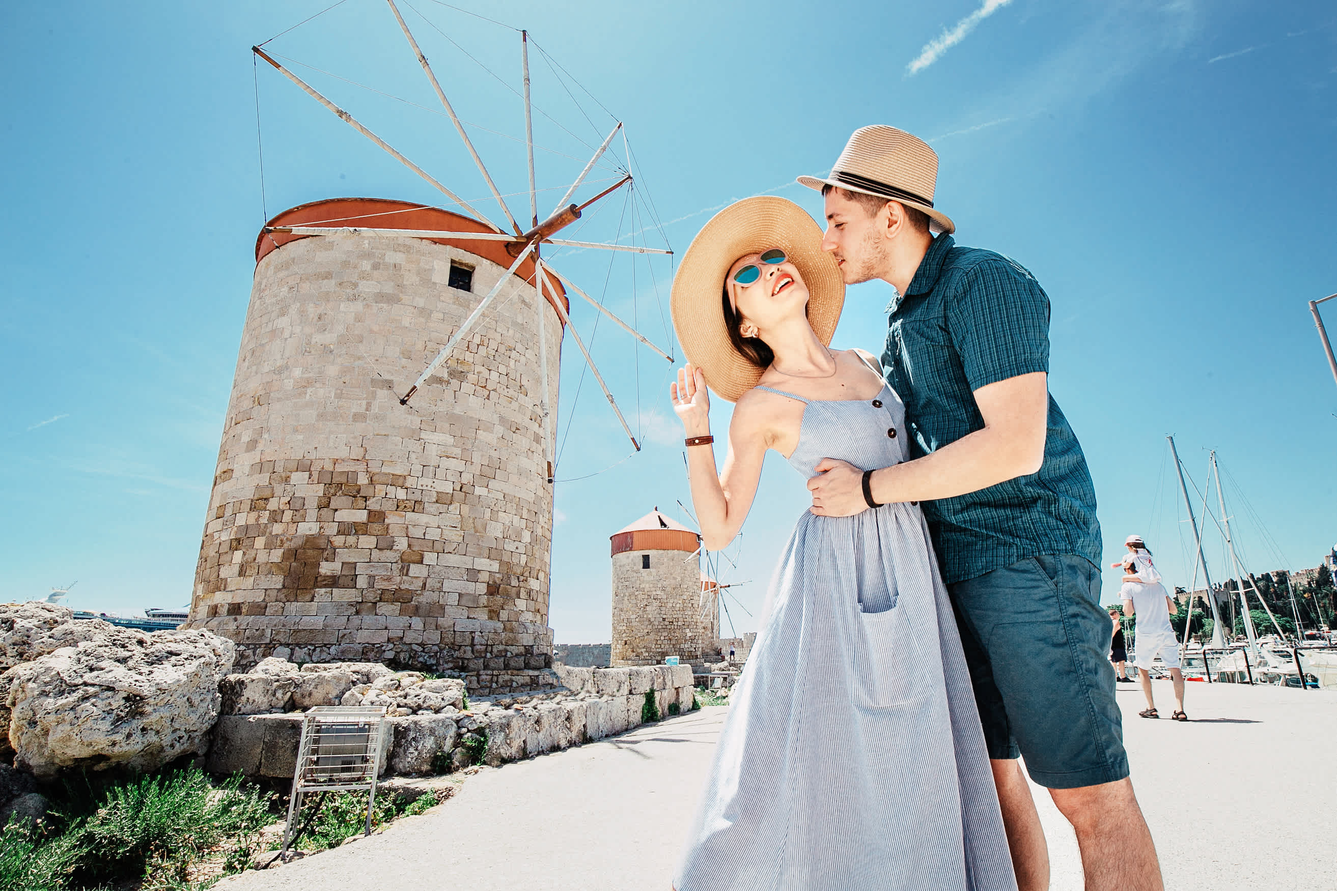 Ein paar Touristen vor den berühmten Windmühlen in Rhodos Stadt, Griechenland.