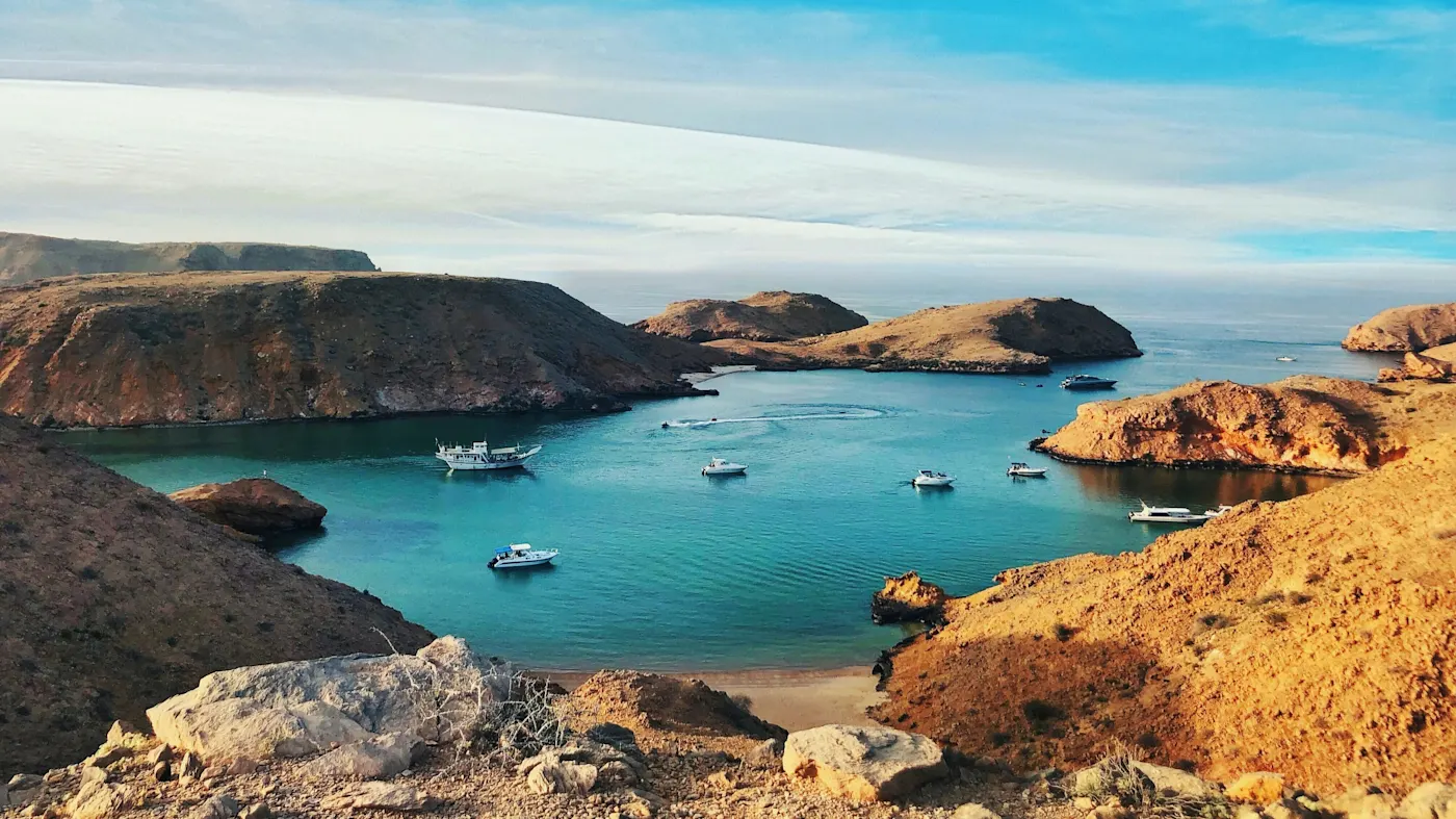 Malerische Bucht mit klarem Wasser, Booten und felsigen Inseln, Bandar Khayran, Oman