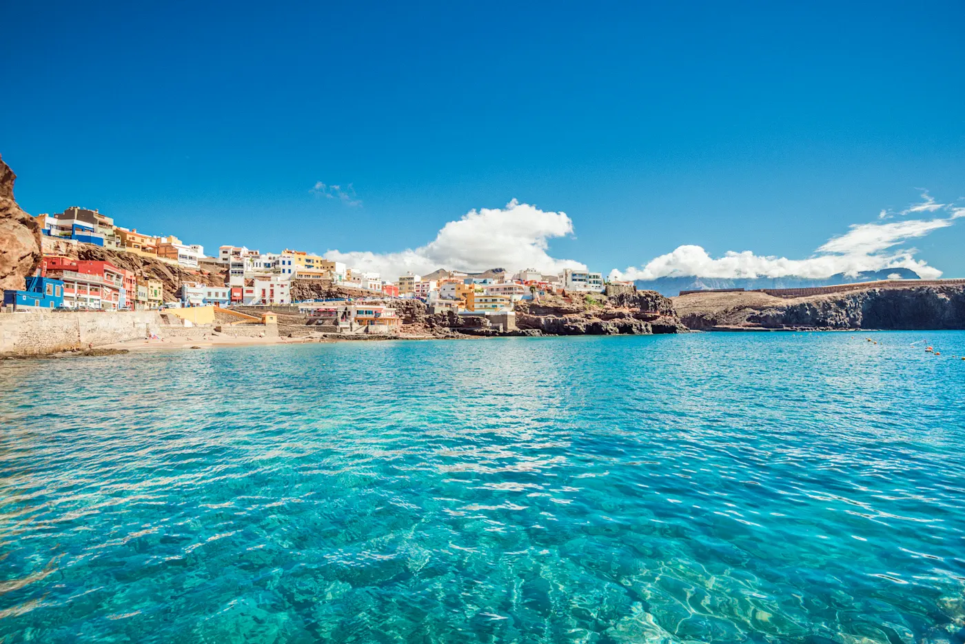 Gran Canaria, Spanien, Europa Bunt gefärbte Häuser am Ufer einer Bucht mit türkisblauem Wasser. Agaete, Gran Canaria, Spanien.