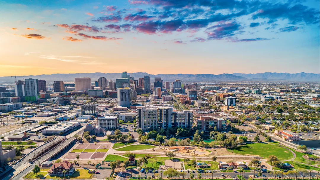 Luftaufnahme der Skyline von Phoenix bei Sonnenuntergang, mit Blick auf die Berge im Hintergrund. Phoenix, Arizona, USA.