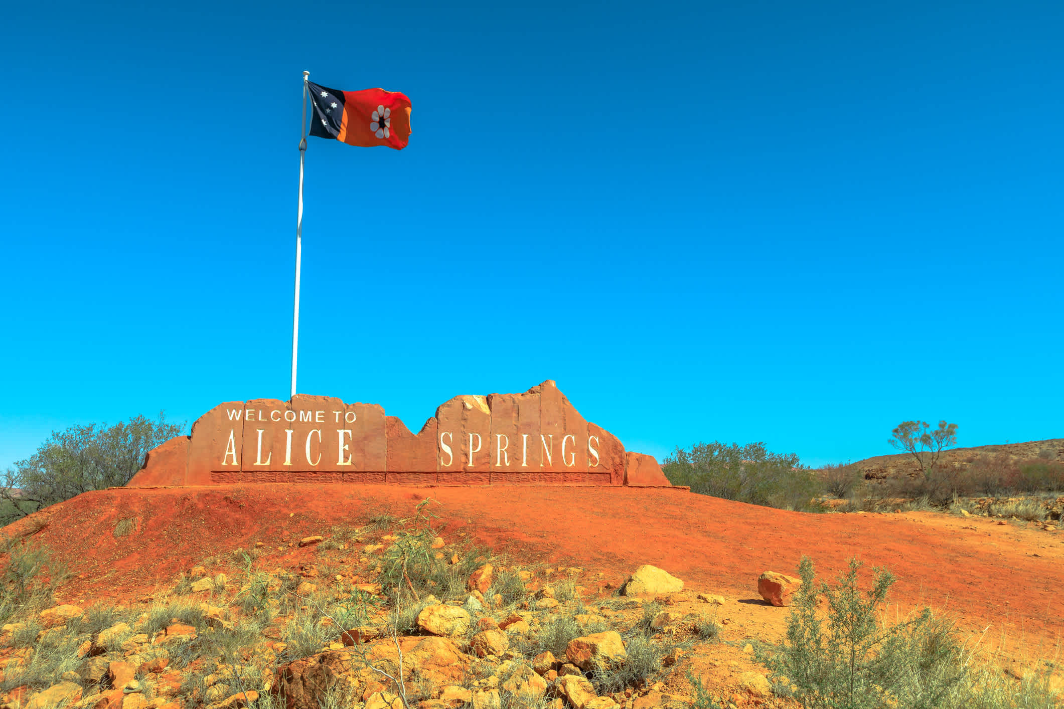 Alice Springs Willkommensschild und australische Flagge von Northern Territory in Zentralaustralien. 
