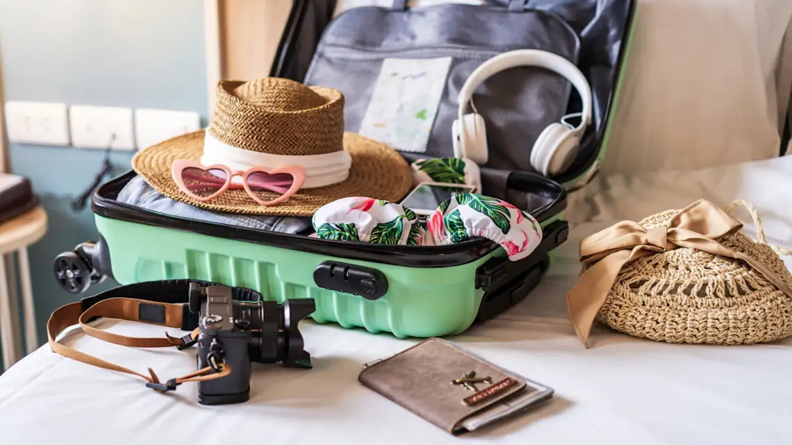Liste der Dinge, die man für eine Reise auf die Bahamas einpacken sollte Koffer mit Zubehör und Reiseartikeln, um sich auf den Urlaub vorzubereiten.