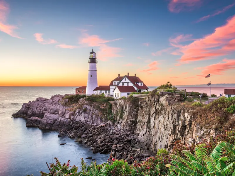 Leuchtturm auf Felsen mit malerischem Sonnenuntergang und Meerblick. Portland, Maine, USA.