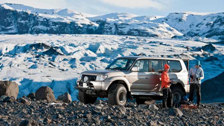 Zwei Reisende vor einem Auto in Island