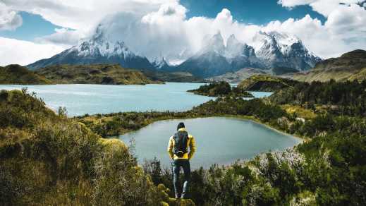 South America, Chile, Patagonia, view of a hiker in Torres del Pain with a sweeping view of snowy mountains, glacial lakes, and forest.