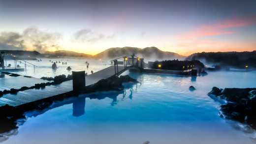 Europe, Iceland, the warm waters of Blue Lagoon steam against a sunset sky.