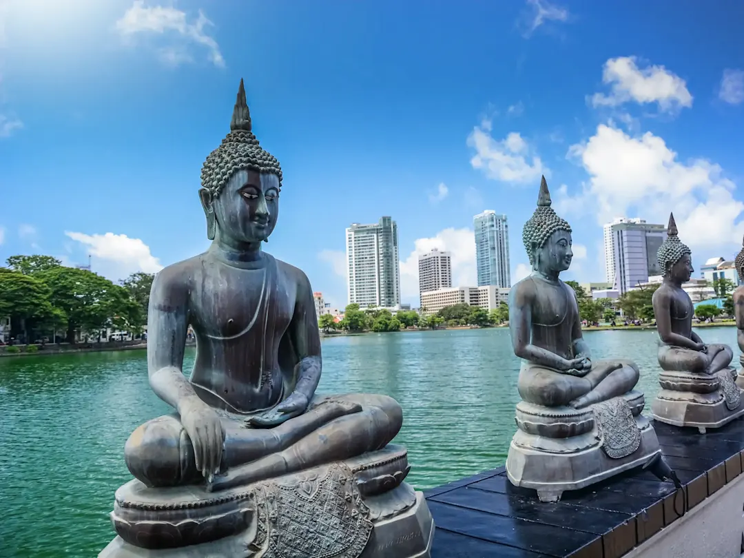  Buddha-Statuen mit moderner Skyline im Hintergrund. Colombo, Westprovinz, Sri Lanka.