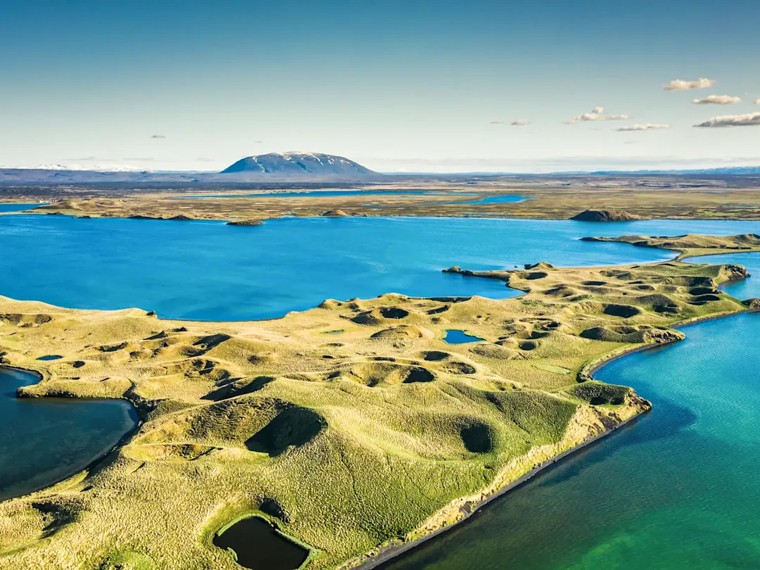 Vulkanische Seenlandschaft mit grünen Hügeln und tiefblauem Wasser. Mývatn, Island.