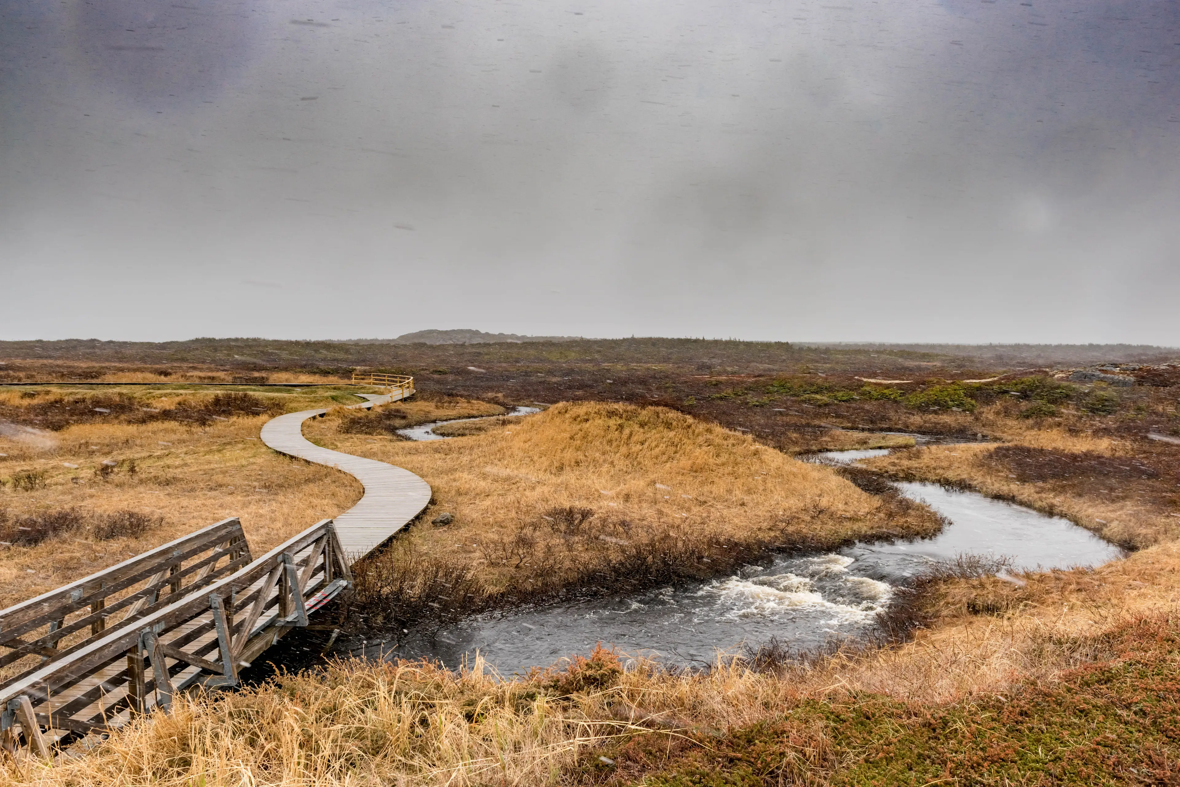 Kanada, Neufundland, St Anthony, Anse aux Meadows Holzpfad und Brücke über einem Bach in einer trockenen Graslandschaft