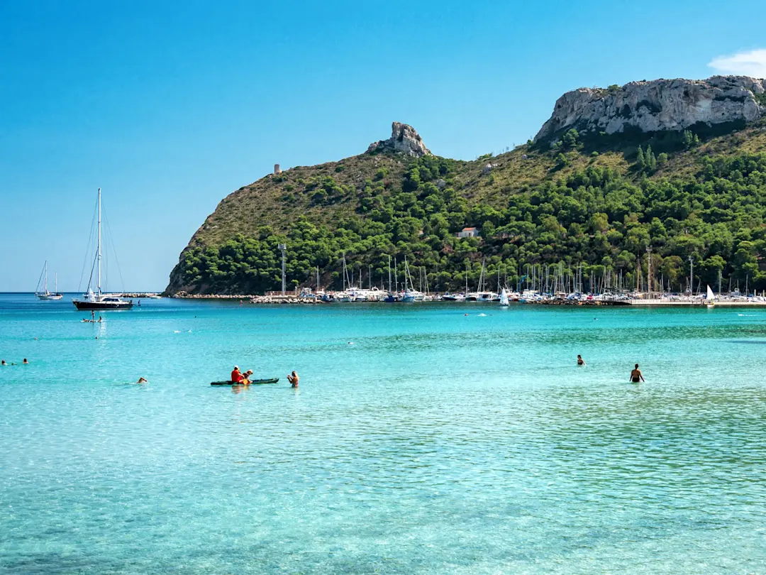 Kristallklares Wasser und grüne Hügel am Strand von Poetto. Cagliari, Sardinien, Italien.