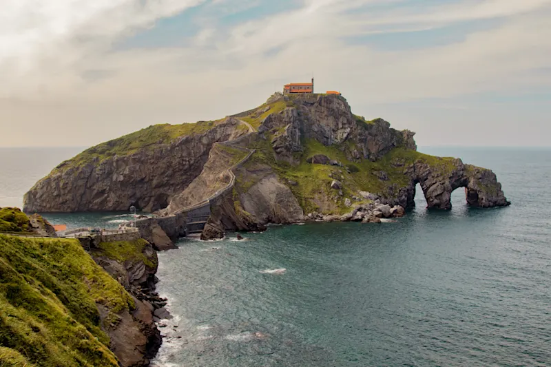Abenddämmerung über Gaztelugatxe mit Kapelle und langer Brücke. Bermeo, Baskenland, Spanien.