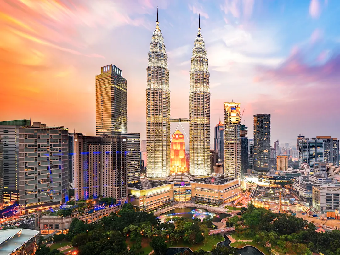 Beleuchtete Zwillingstürme und Skyline bei Sonnenuntergang. Petronas Towers, Kuala Lumpur, Malaysia.