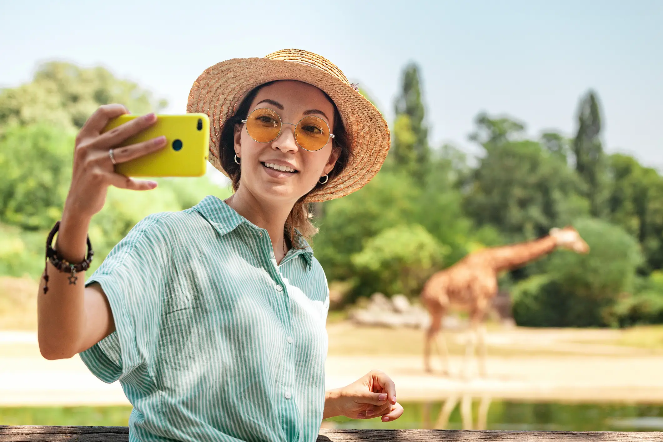 Safari Selfie Ein Mädchen macht ein Selfie mit einer Giraffe im Hintergrund.
