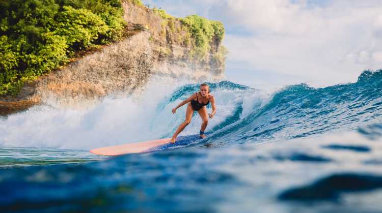 Fille surfant sur une longue planche de surf. Femme dans l'océan en train de surfer. Surfeur et vague de l'océan