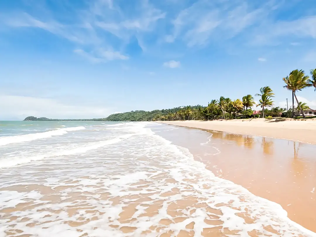 Sandstrand mit Palmen und Wellen, Mission Beach, Queensland, Australien.
