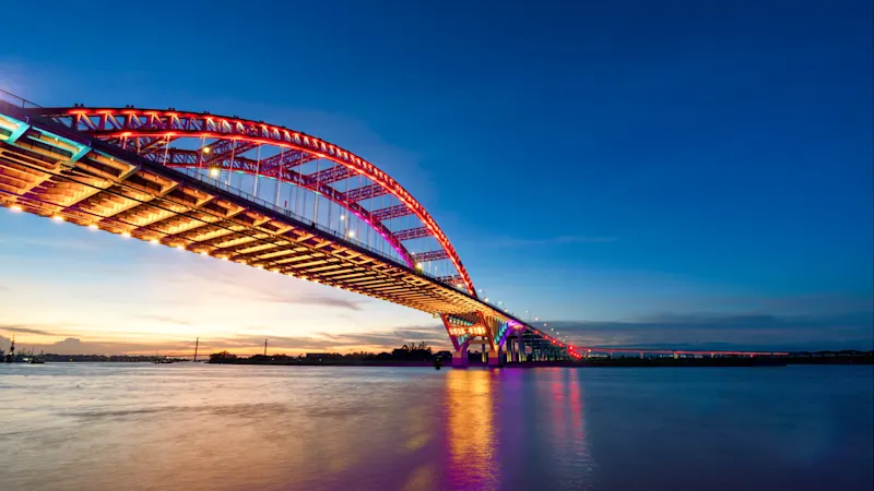 Hai Phong, Vietnam Beleuchtete Brücke mit bunten Lichtern über einem Fluss bei Sonnenuntergang. Hai Phong, Vietnam.